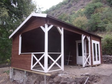 Barevná kombinace bílé a tmavě hnědé lazury, kterou jsme použili při povrchové úpravě dřeva přidá malé chatě na atraktivitě